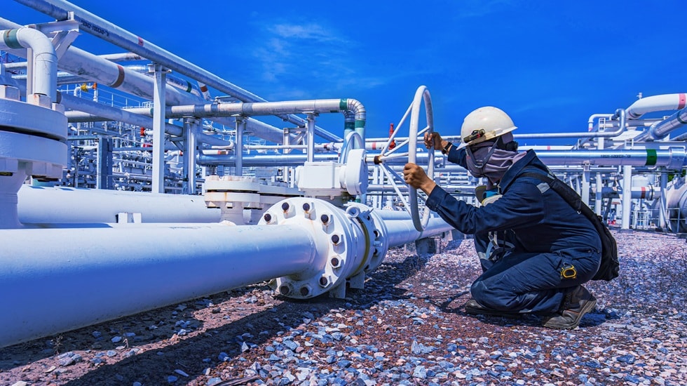 An engineer wearing protective equipment inspecting industrial pipelines