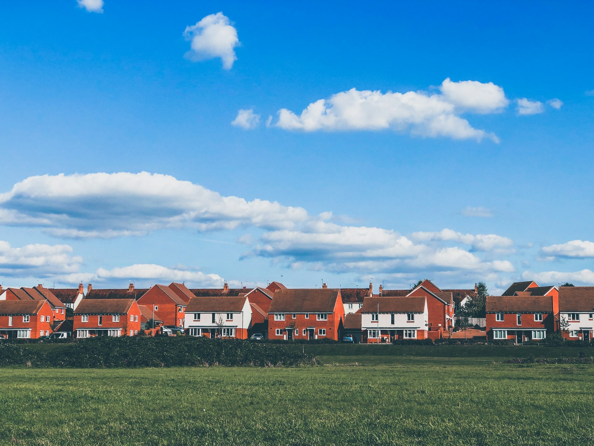 A row of newly built family homes beside an open green field