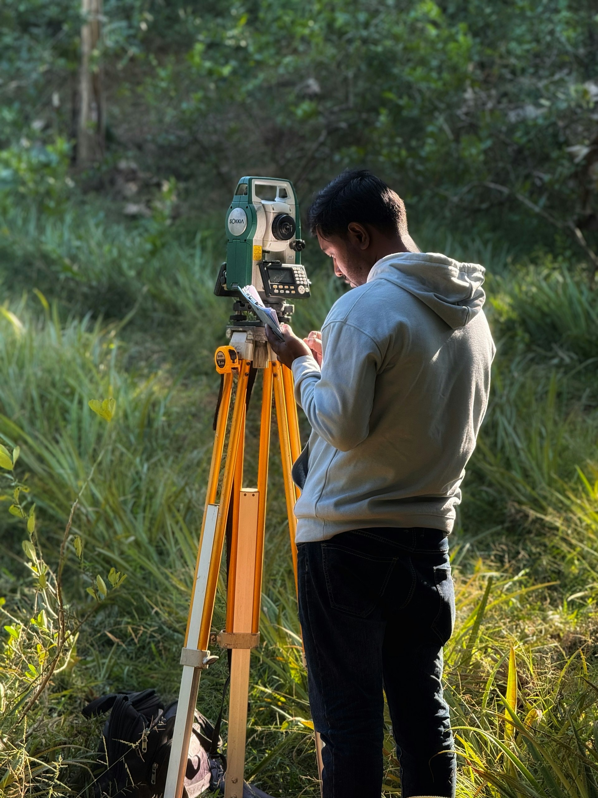Land surveyor using a total station on open, undeveloped land