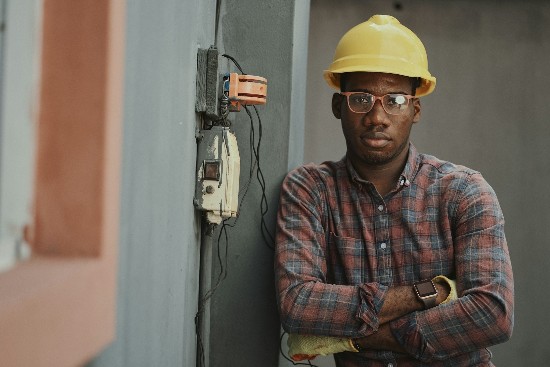 Worker wearing a hard hat, safety glasses and work gloves beside electrical equipment