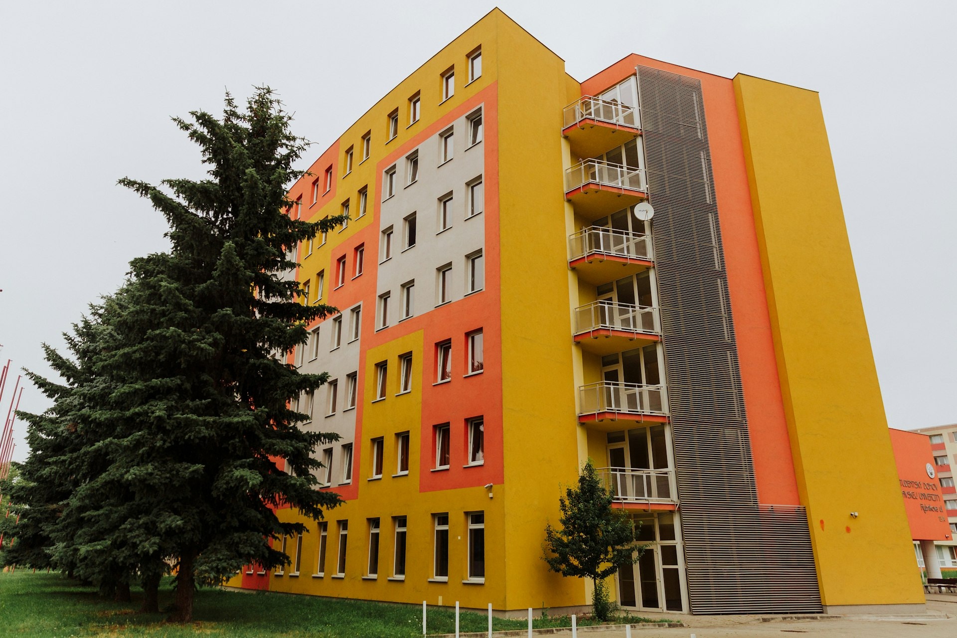 Multi-storey student residence building with balconies, set among trees